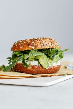 a sandwich with lettuce, cheese and other toppings sitting on a plate