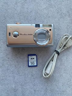 a digital camera sitting on top of a carpet next to a charger and cable