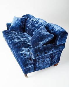 a blue velvet couch with two pillows on it's arms and legs, in front of a white background