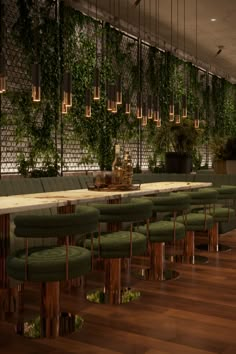 a long table with green chairs and plants on the wall behind it in a restaurant