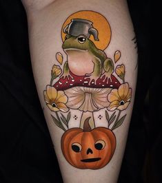 a frog sitting on top of a mushroom next to a pumpkin