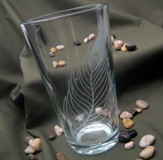 a glass filled with rocks and water on top of a cloth covered table next to shells