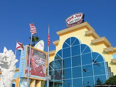 an image of a building with flags flying in the wind and blue sky behind it