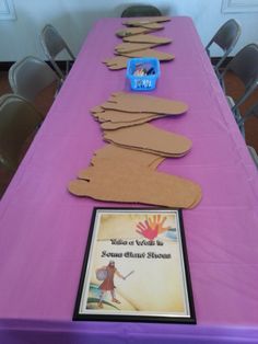 there is a long table with paper cutouts on it and a book about jesus