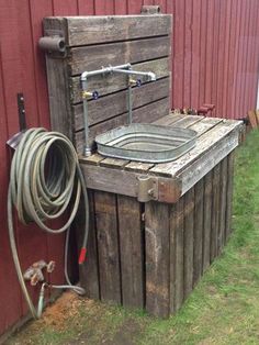 an old wooden tub sitting next to a red building with a hose attached to it