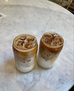 two iced drinks sitting on top of a marble table