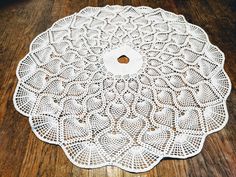 a white doily sitting on top of a wooden table next to a brown floor