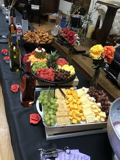 several trays of different types of food on a table with wine bottles and flowers