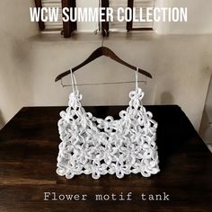 a white crochet purse hanging on a wooden hanger with the words flower nottitank below it