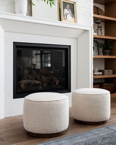 two white stools sitting in front of a fireplace