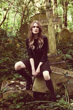 a woman sitting on top of a grave in the woods