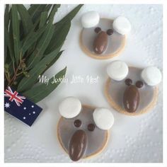 three cookies decorated with chocolate and marshmallows are on a white tablecloth