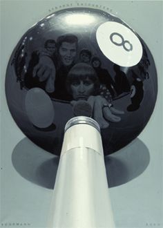 a black and white photo of people behind a large ball with the number eight on it