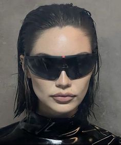 a woman with black hair and sunglasses on top of her head, wearing shiny clothing