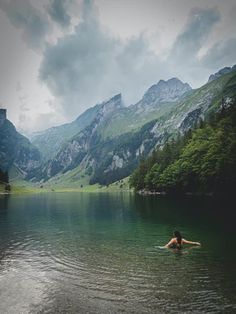 a person swimming in a lake surrounded by mountains