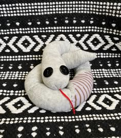 a white stuffed animal laying on top of a black and white rug with an eye patch