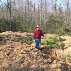 a man standing on top of a dirt hill in the middle of a wooded area