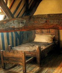 an old wooden bed in a room with beams on the ceiling and wood flooring