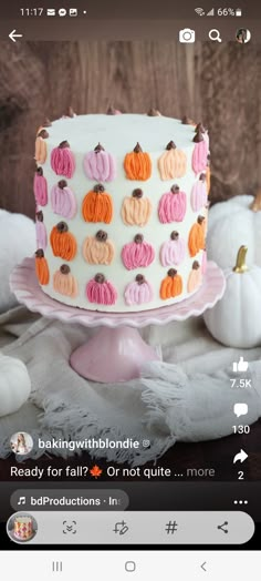 a white cake sitting on top of a table next to stuffed animals and pumpkins