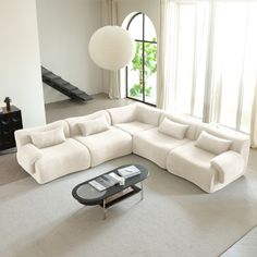 a living room with a large sectional couch and coffee table in the middle, next to a staircase