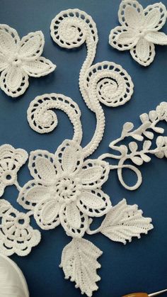 white crocheted flowers and leaves on a blue surface