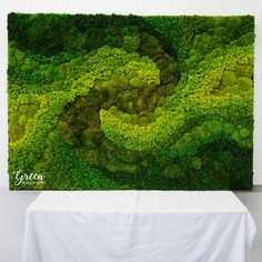 a green wall with moss growing on it and a white table in front of it