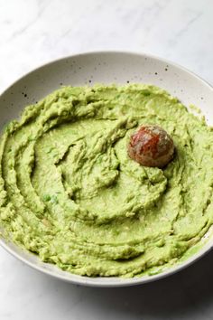 a white bowl filled with guacamole and a piece of meat in the middle