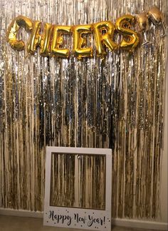 a photo frame sitting in front of a wall with foil streamers and the word cheers on it