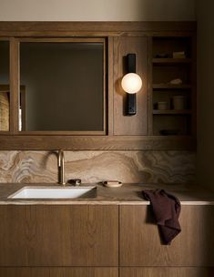 a bathroom with wooden cabinets and a white sink under a large mirror on the wall