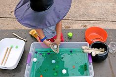 child using skeleton hands to pick up a ball from green water