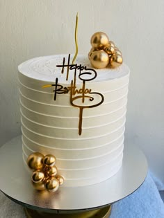 there is a white cake with gold decorations on the top and happy birthday written on it