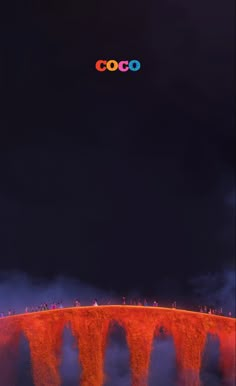 people are standing on the edge of a bridge at night with neon lights above it