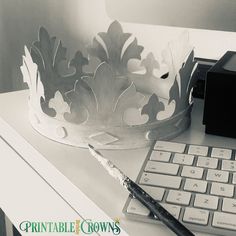 a black and white photo of a desk with a keyboard, mouse and a paper crown