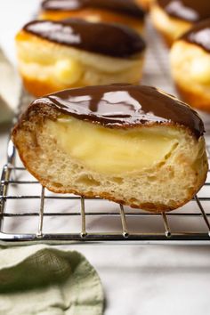 chocolate covered doughnuts on a cooling rack with other pastries in the background