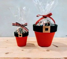 two red and black baskets filled with candy wrapped in cellophane, sitting on top of a wooden table