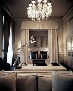 a living room filled with furniture and a chandelier hanging over the top of it