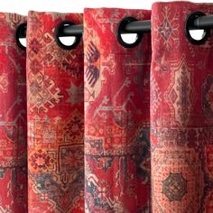 three red curtains hanging on the side of a window with decorative designs and black handles