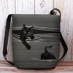 a black cat sitting in the middle of a striped bag on top of a wooden table