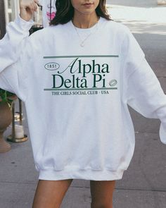 the adpi (social club ♡ Super soft sweatshirt comes in unisex sizing! Reference the size chart for additional details. It is recommended to SIZE UP for an oversized fit   ♡ Sweatshirt comes in white with a forest green print. Please check listing photos for color reference! ♡ Please make sure you are ordering for the correct sorority before placing an order! We are unable to accept returns or exchanges for this since all items are made to order.   ♡ INSTRUCTIONS FOR CARE:  1. Turn inside out bef Cotton Sorority Sweatshirt With Graphic Print, Cotton Sweatshirt With Graphic Print For Sorority, Casual Letter Print Sweatshirt For College Events, Sorority Long Sleeve Graphic Sweatshirt, Sorority Graphic Print Long Sleeve Sweatshirt, Sorority Crew Neck Top For Streetwear, Sorority Sweatshirt With Letter Print In Relaxed Fit, Sorority Letter Print Sweatshirt In Relaxed Fit, Sorority Style Spring Sweatshirt With Letter Print