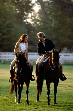 two people riding on the backs of brown horses