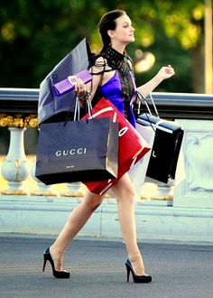 a woman walking down the street with shopping bags in her hand and wearing high heels