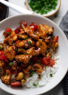 a white bowl filled with chicken and rice on top of a table next to chopsticks