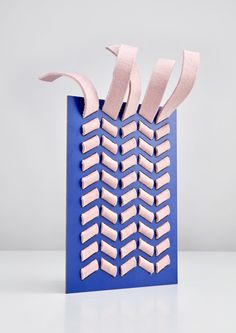 a blue paper bag with pink strips sticking out of it's sides on a white surface