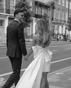 a man and woman walking down the street with their arms in the air holding hands