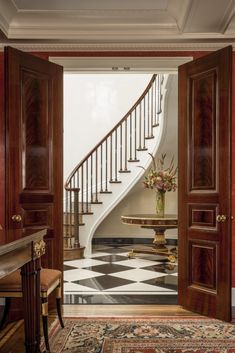 an entry way leading to a foyer with marble flooring and wooden doors that lead up to the staircase