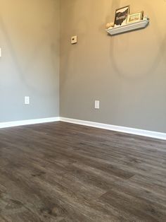 an empty room with hard wood floors and gray walls