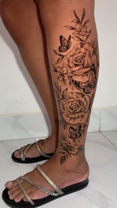 a woman's leg with flowers and butterflies on it, while she is wearing sandals