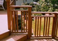 a deck with wooden railings and chairs on the other side, overlooking a yard