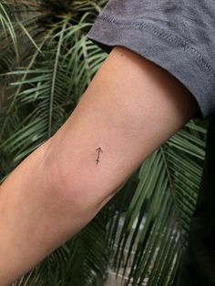 a person's arm with a small cross tattoo on the left side of their arm