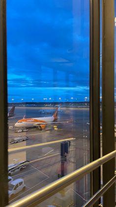 an airport terminal with planes parked on the tarmac at dusk, as seen through large windows